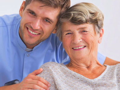 caregiver smiling together with elderly woman