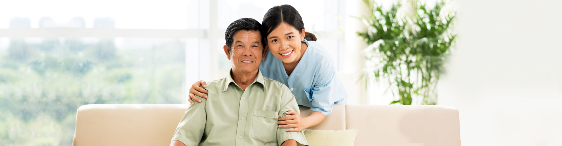 health care worker smiling with elderly man sitting on couch